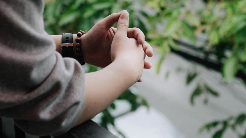 A person clasping their hands outdoors.