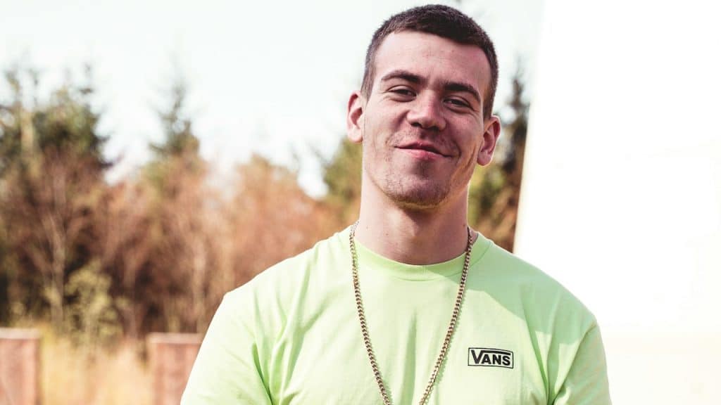 A man in a green crew-neck t-shirt and black pants.