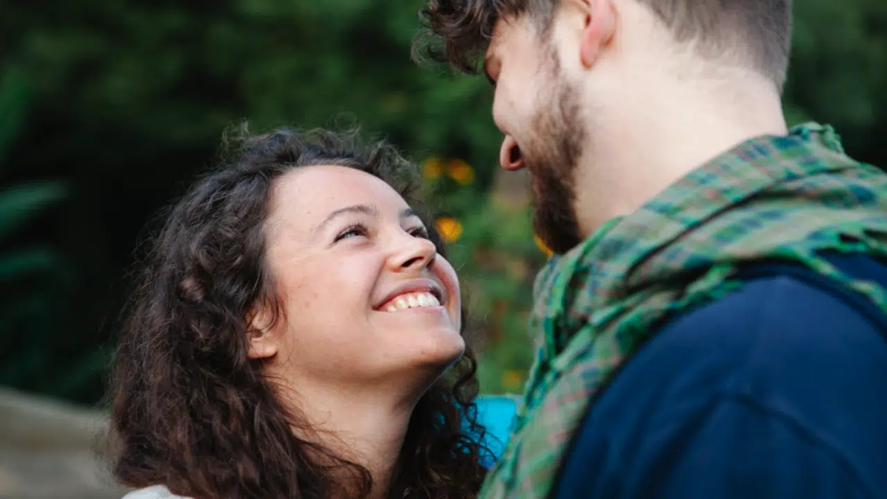 A couple smiling at each other outdoors 