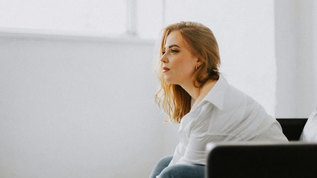 A woman sitting and gazing thoughtfully into the distance.