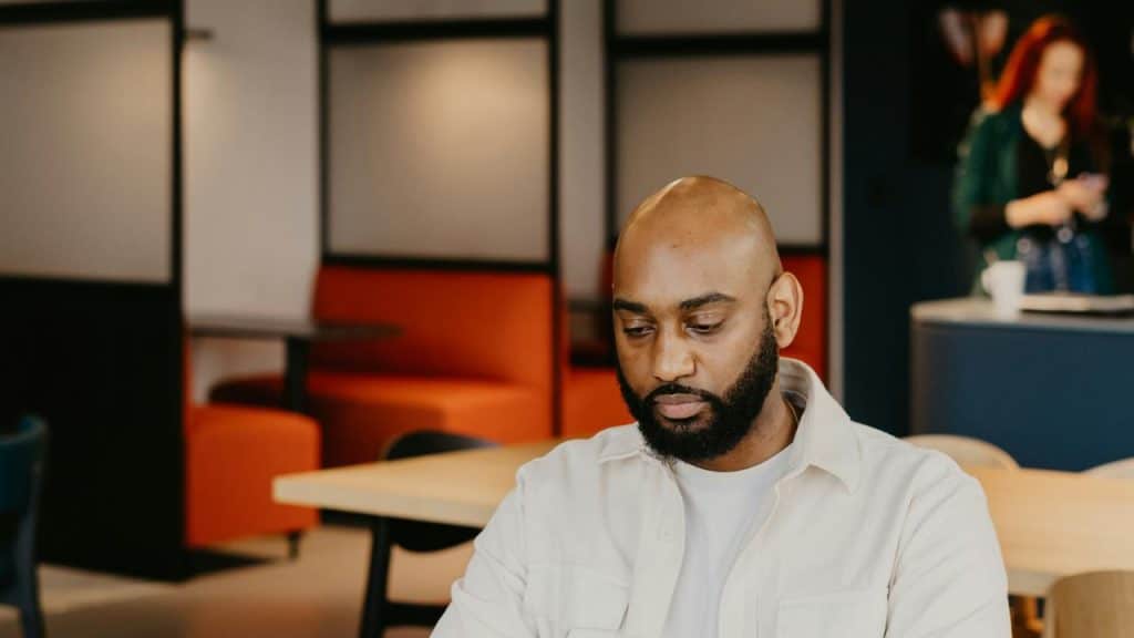 A focused man sitting at a table in a modern workspace.