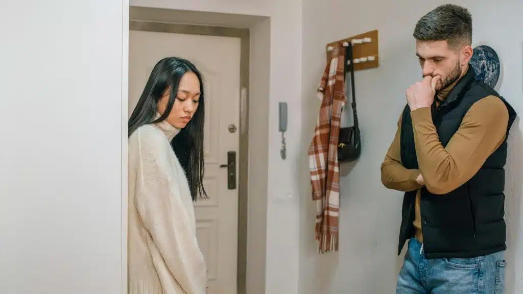 An upset couple standing near the door.