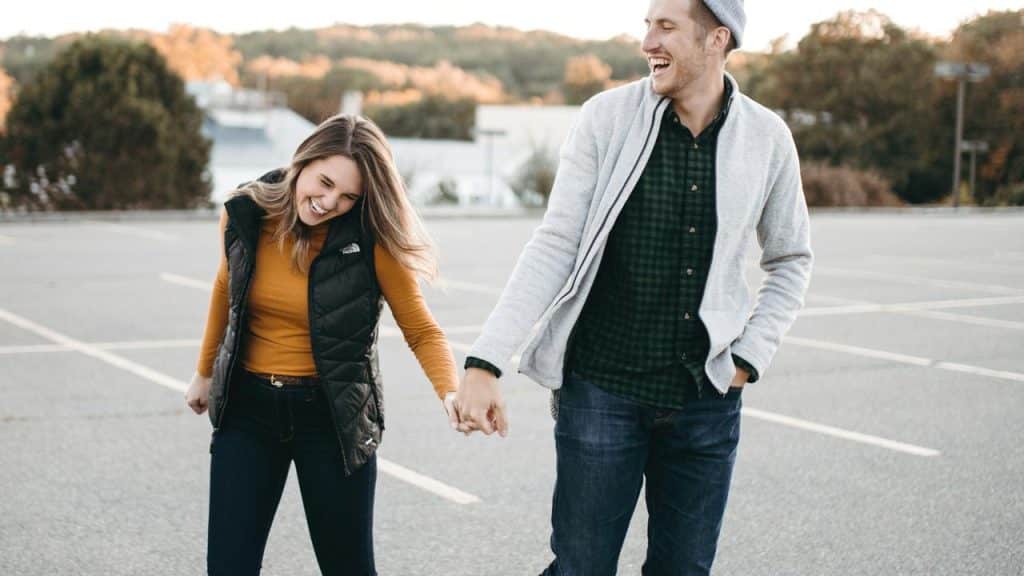 A smiling couple holding hands while walking outdoors.
