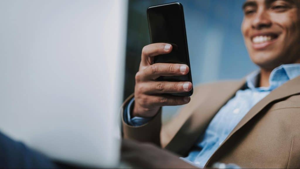 A man smiling while using a phone