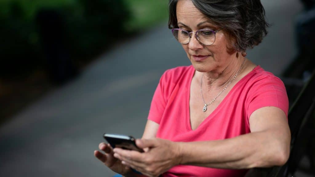 A senior woman using a mobile phone in a park.