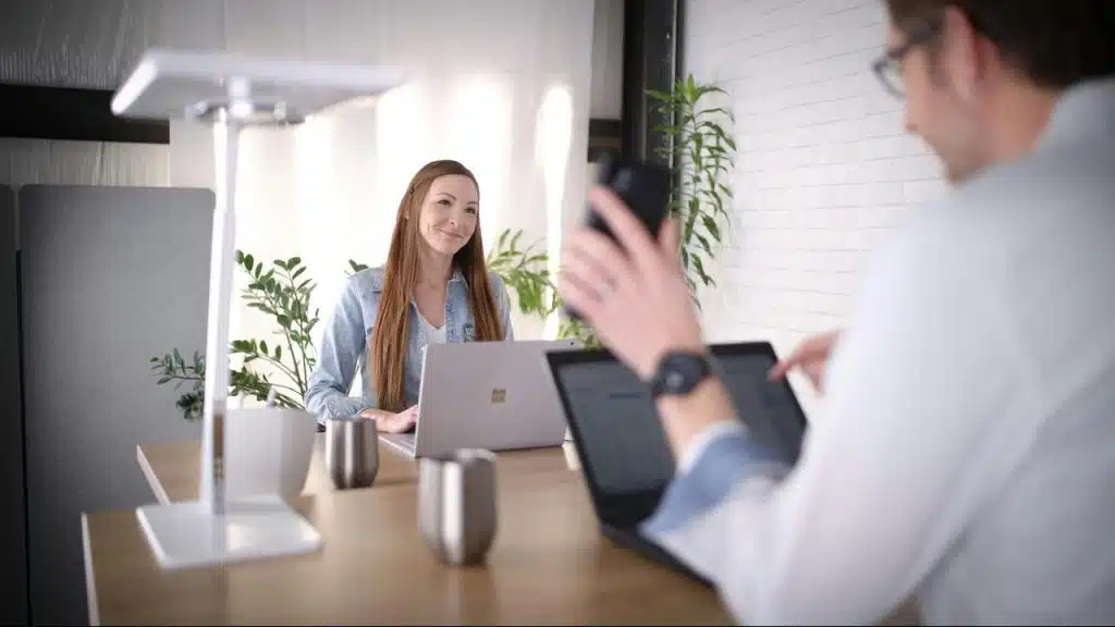 A woman working on a laptop during a modern office meeting.