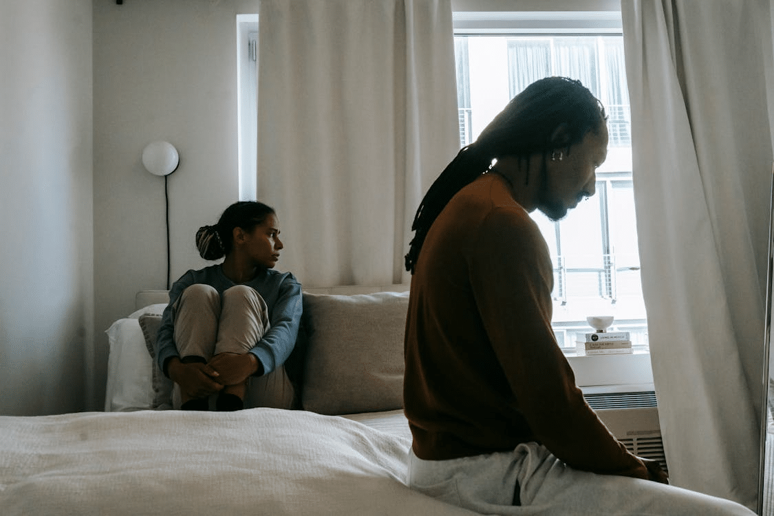 Sad couple during quarrel on bed