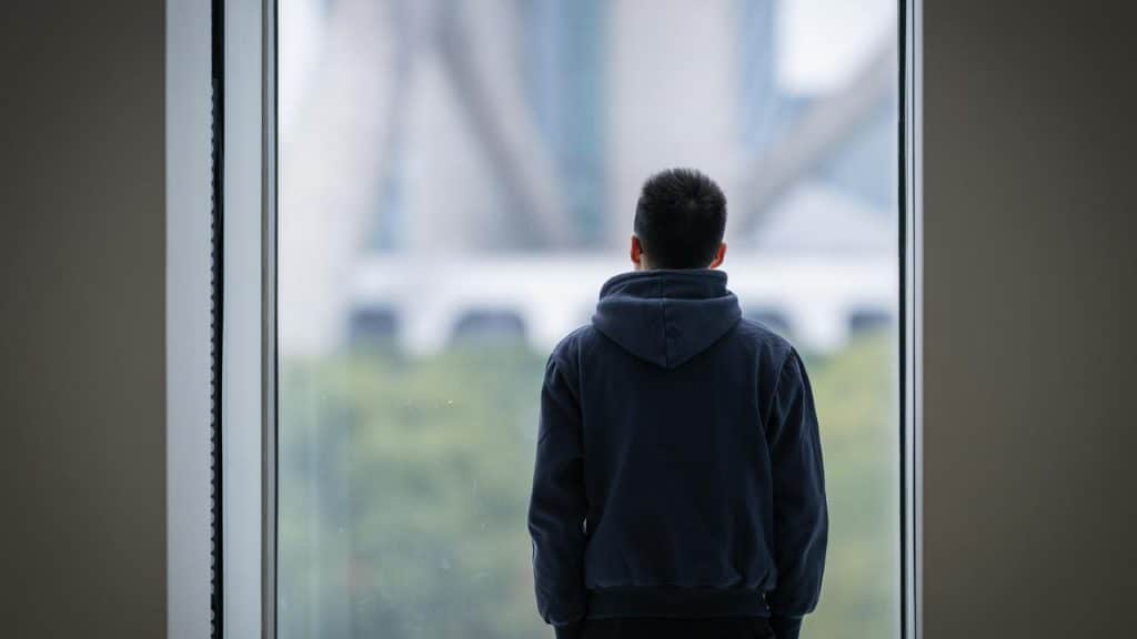 A person standing and looking out through a large window.