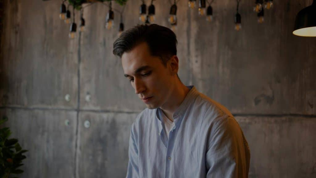 A man looking down thoughtfully in a softly lit room.