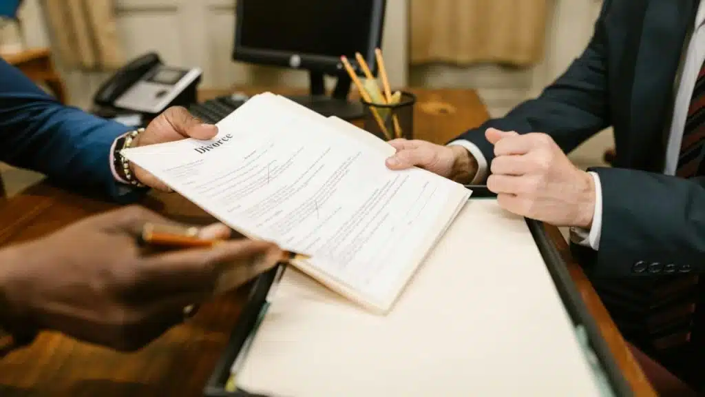 Hands of two people in suits passing a document with the word "Divorce" printed at the top.
