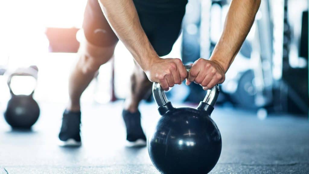 A person doing a push-up using a kettlebell in a gym.