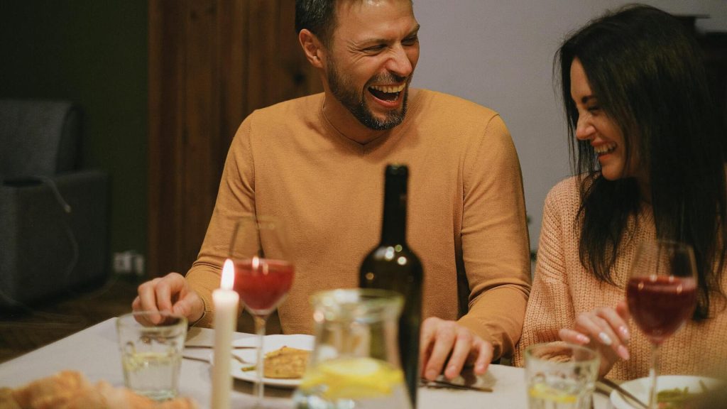 A couple laughing together while having dinner.