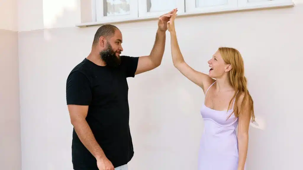 A balding bearded man and a woman high fiving each other and smiling.
