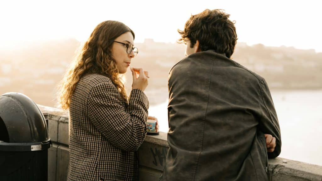 A man and a woman talking while standing next to each other outdoors.