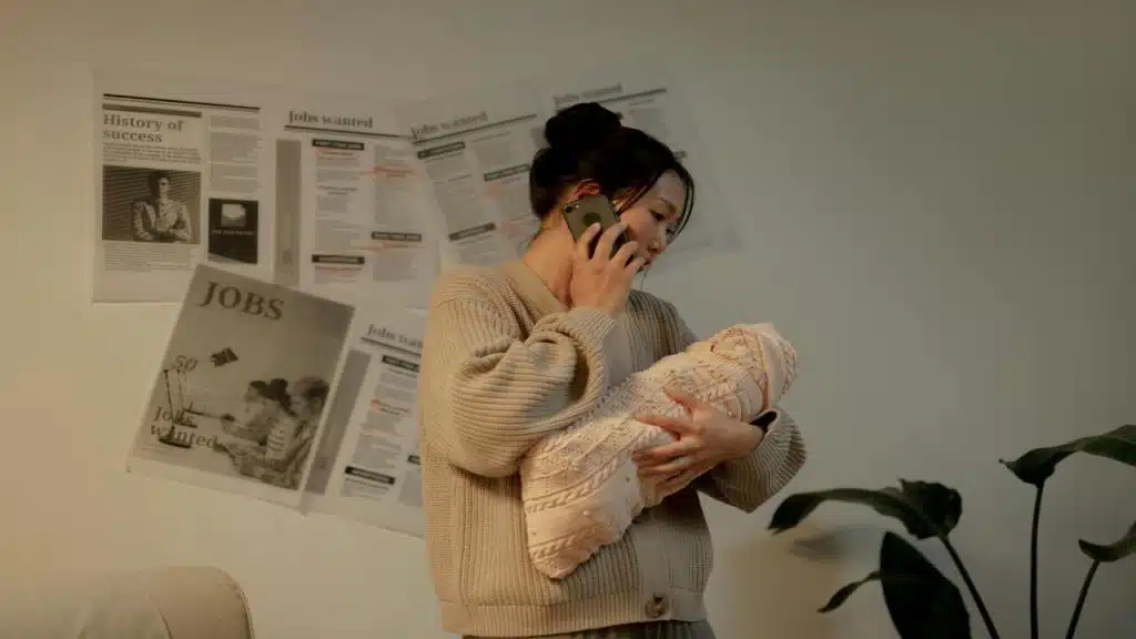 A mom holding her newborn baby while on the phone