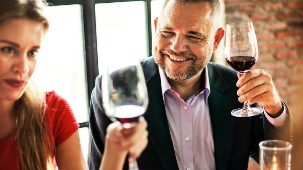 A smiling couple raising wine glasses together at a cozy restaurant table.