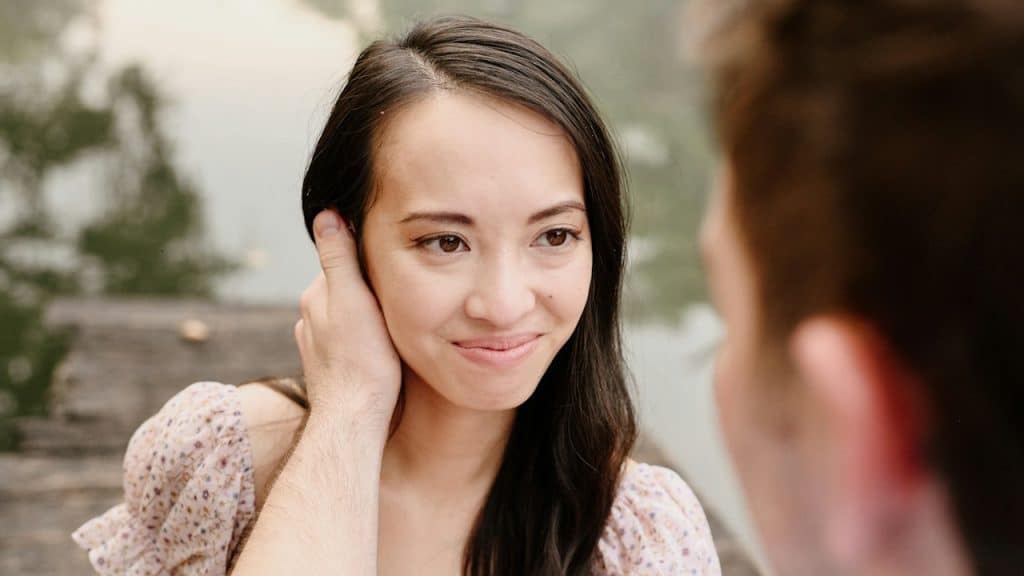 A man stroking a woman’s hair while she smiles.