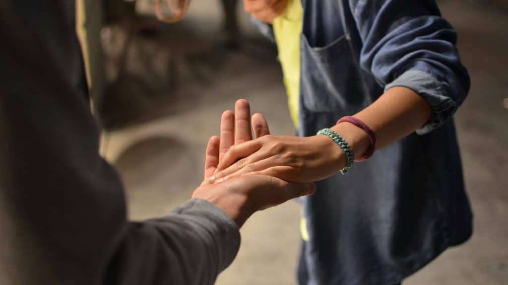 A person’s hand touching another person’s open palm.