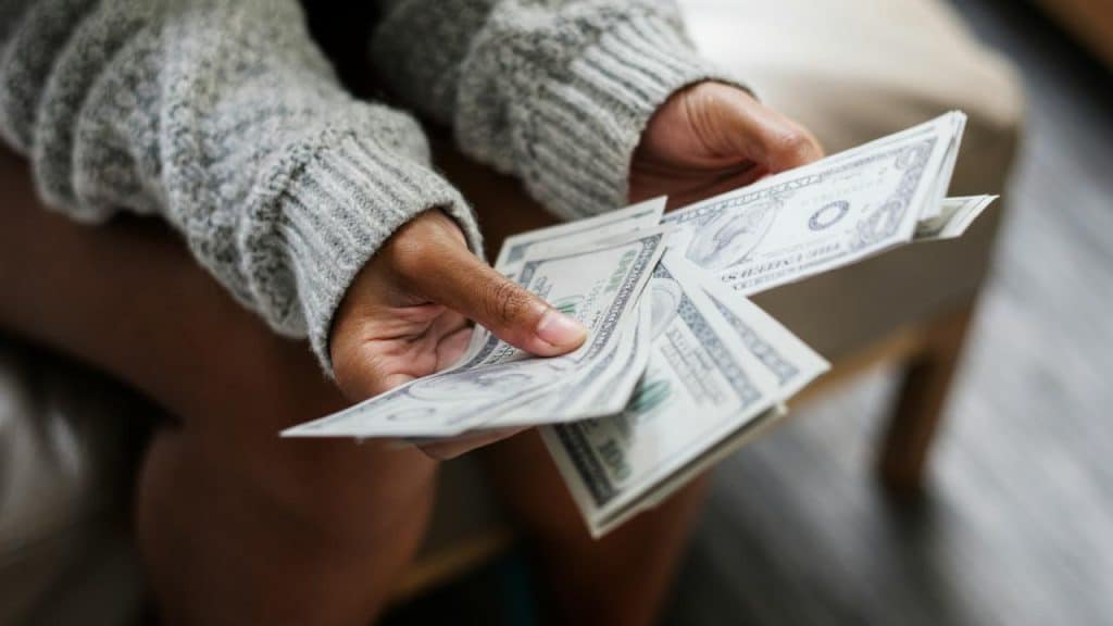 A close-up of a person’s hands counting U.S. dollar bills.