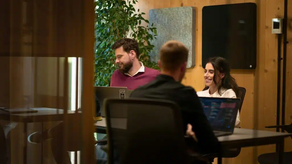 A small team collaborating with laptops in a modern meeting room.