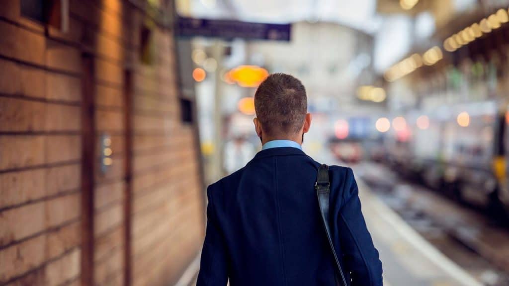 A man in a suit walking on a train platform.