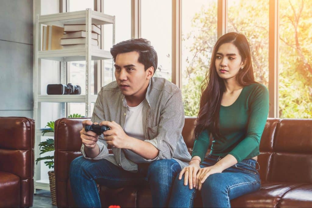 A man playing a game with his wife beside him