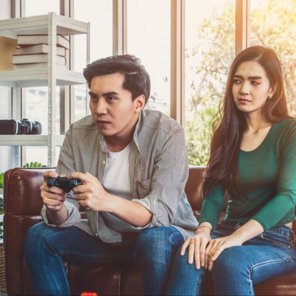 A man playing a game with his wife beside him