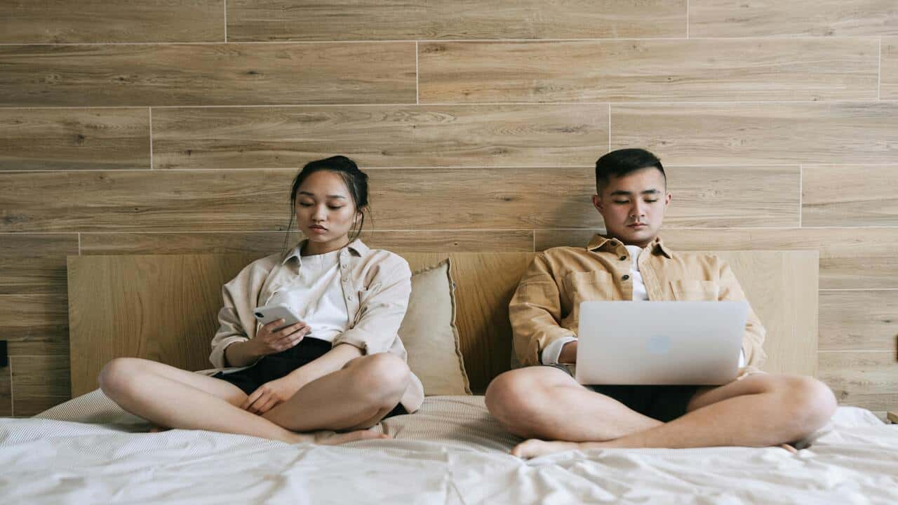 A couple not looking at each other in bed