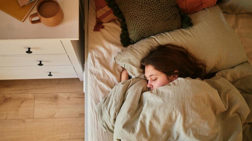 A person sleeping peacefully under blankets in a cozy bedroom.