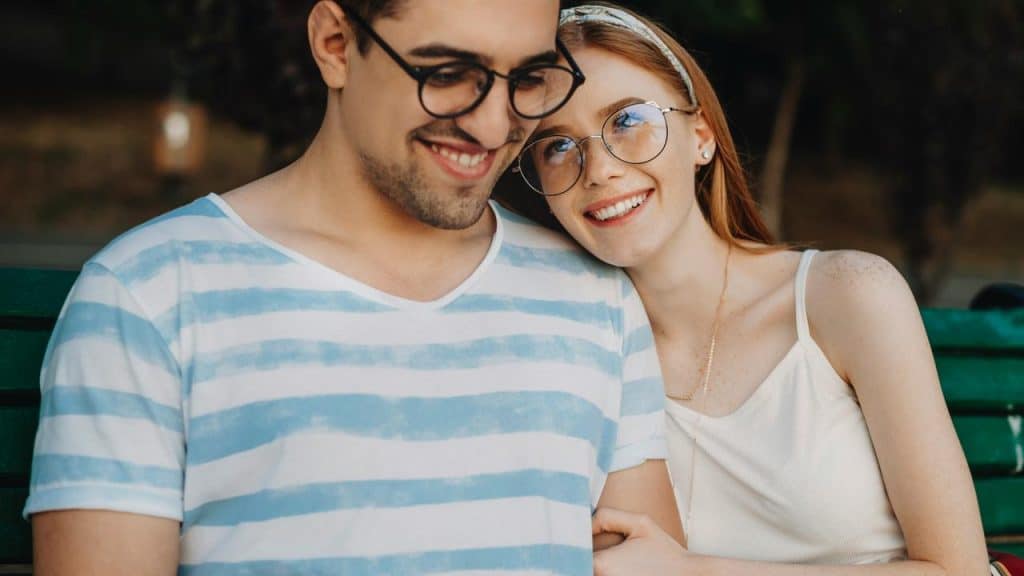 A smiling couple sitting closely together on a park bench.