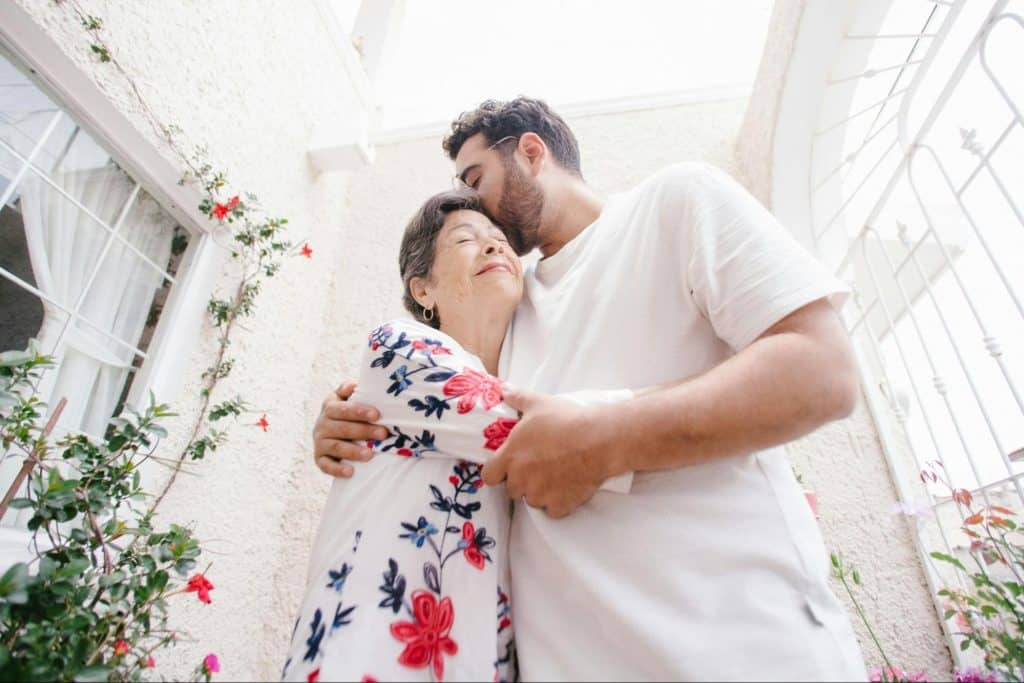 A man kissing his mother’s head