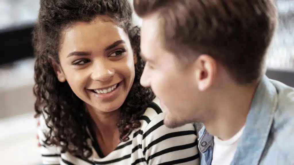 A woman smiling warmly at a man during a close conversation.