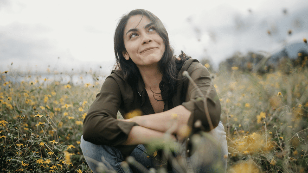 A happy woman sitting on a field of flowers