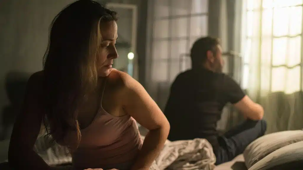 An unhappy couple sitting on the bed after a fight.