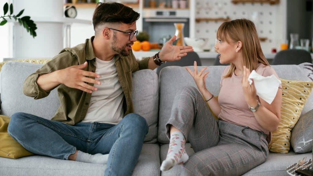A newly married couple fighting with each othersitting at a couch