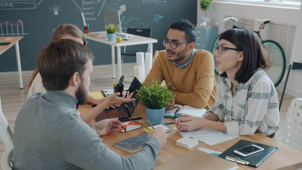 A group of coworkers discussing ideas around a table in a modern office.