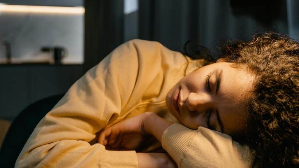 A woman sleeping with her head resting on folded arms.