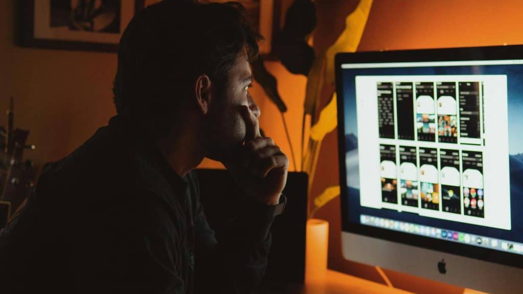 A man looking at a computer screen in a dark room.