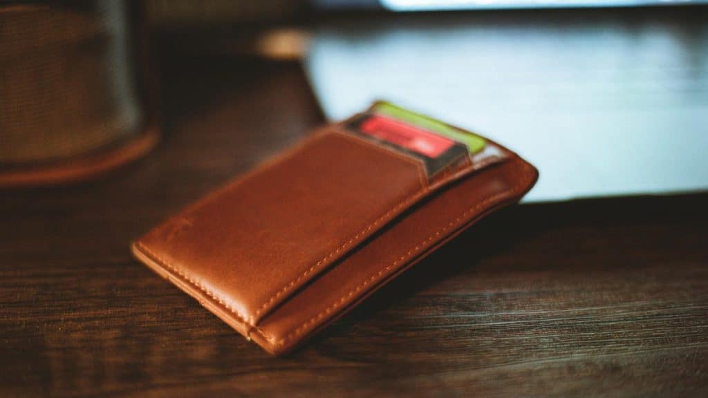 A brown leather wallet with cards on a table.