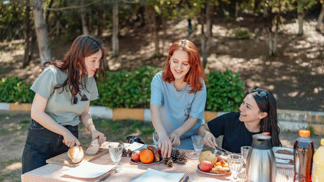 A group of women enjoying a picnic and preparing food outdoors.