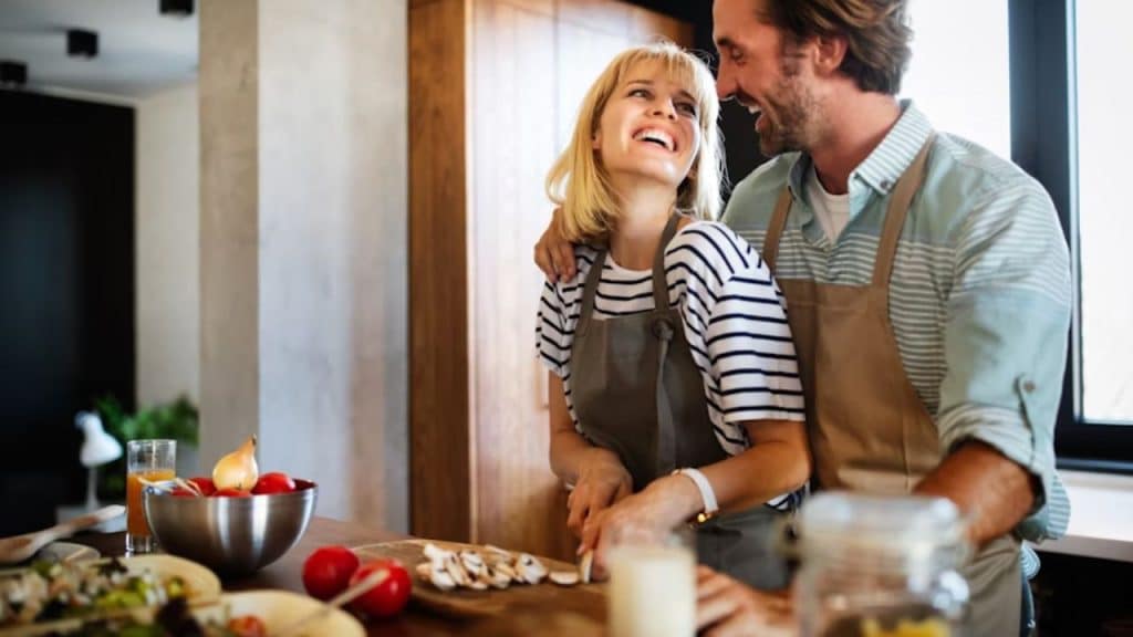 A couple cooking together, laughing in the kitchen