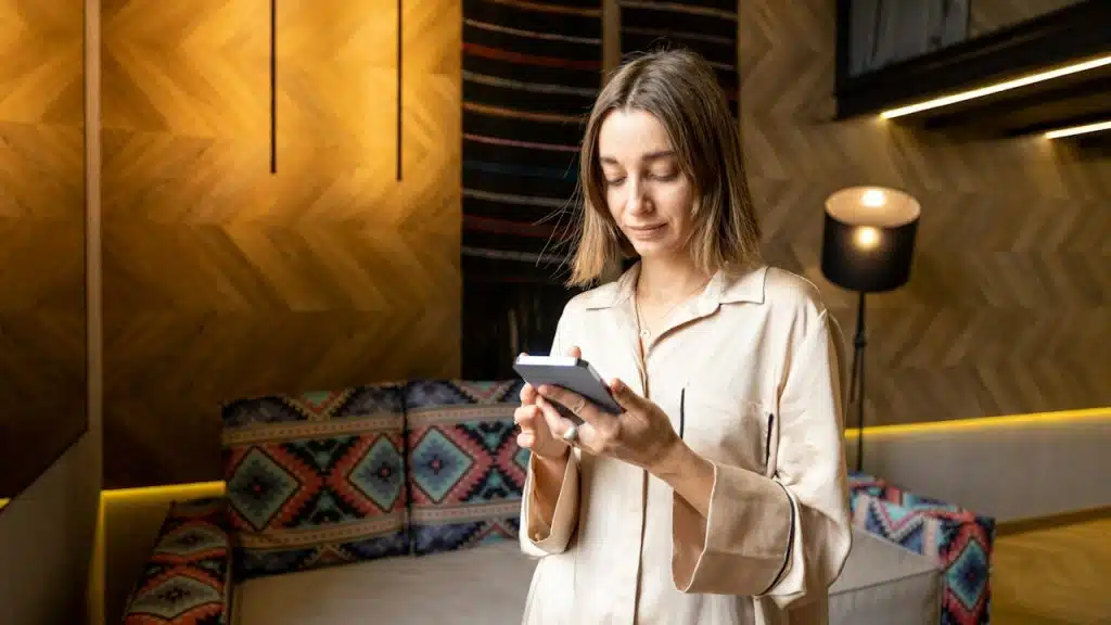 A woman looiking at her phone while standing in her pajamas.