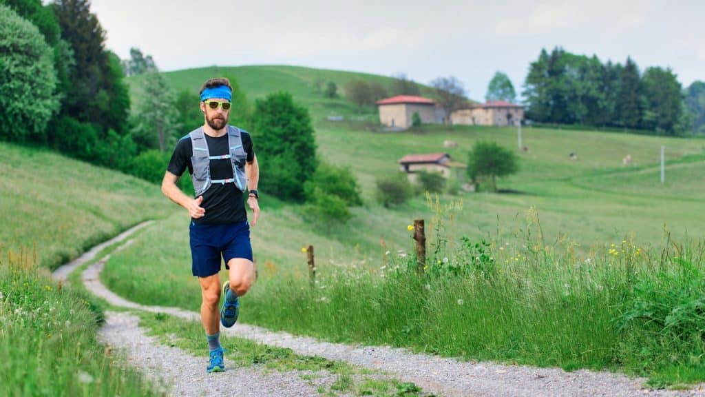 A man wearing sunglasses and shorts is running at a runway in a countryside.