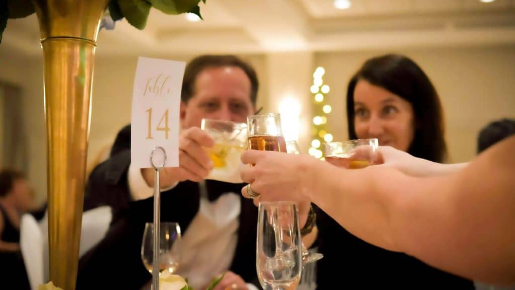 A group of guests clinking glasses at a formal dinner table.