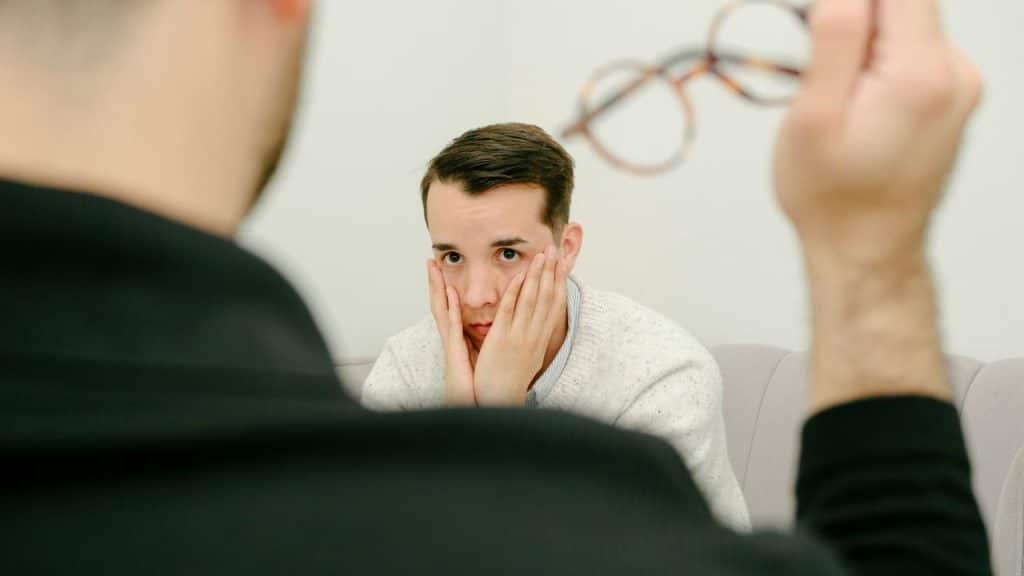 A worried man holding his face.
