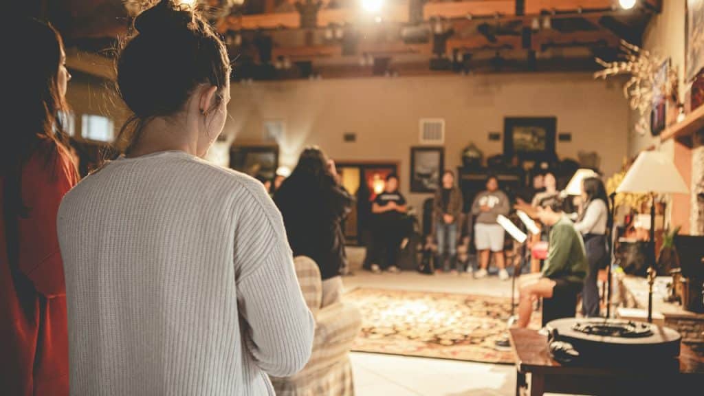 Two women standing in a hall filled with people.