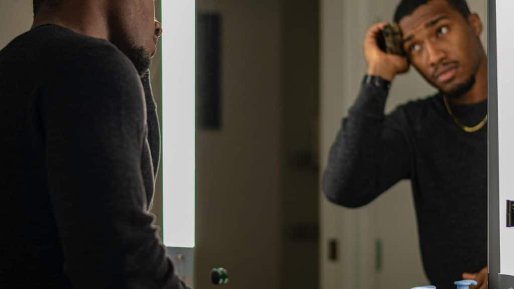 A man adjusting his hair while looking in a mirror.