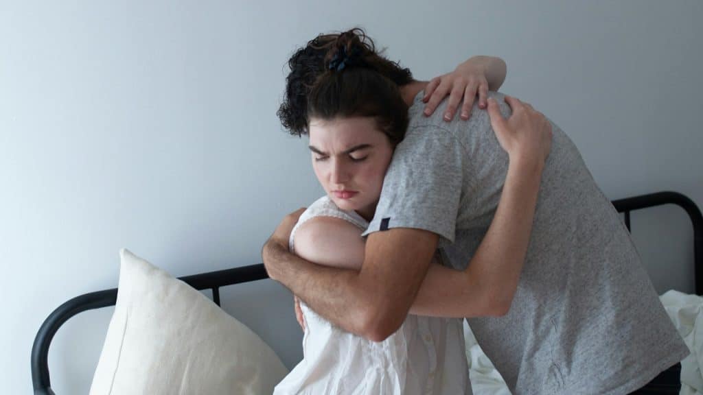 A man hugging a woman on top of a bed.