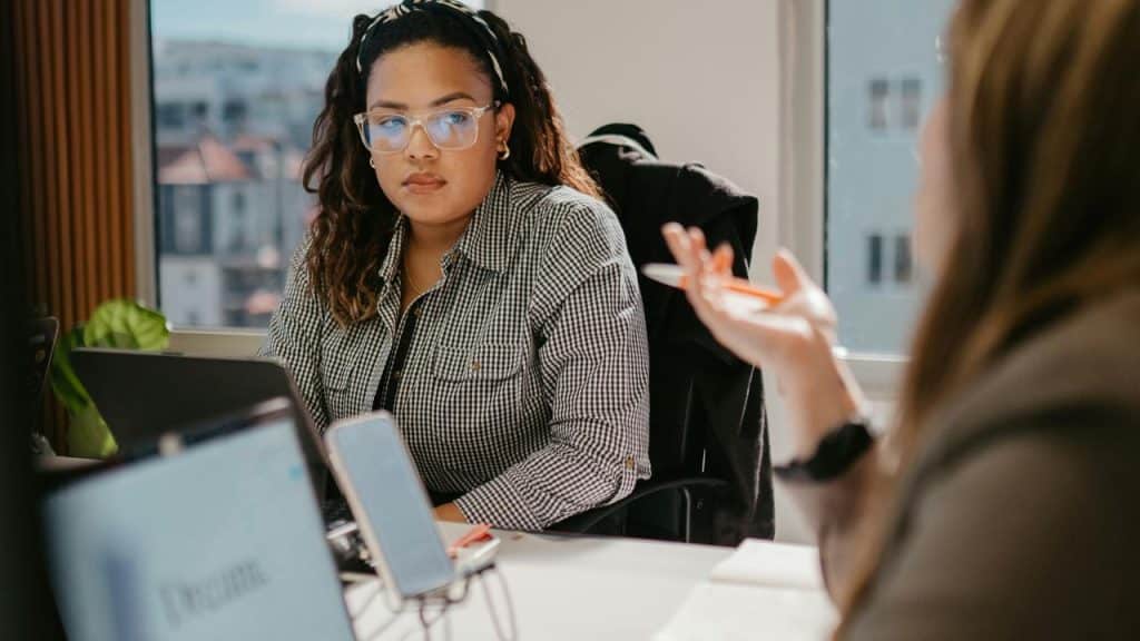 A woman listening thoughtfully during a work discussion at a desk.
