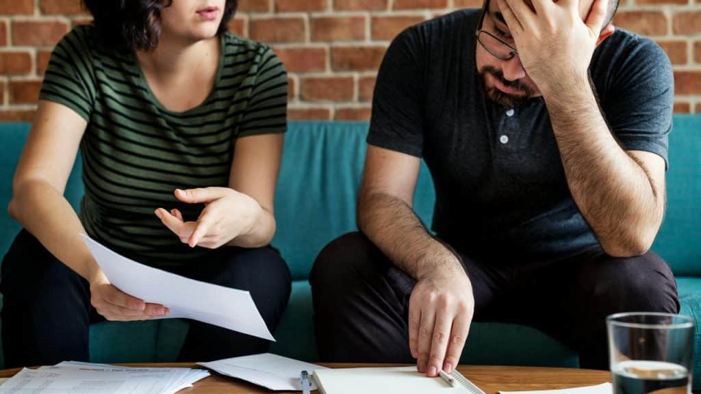 A couple reviewing papers together at a table in a living room.